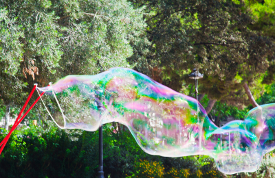 Performer che crea bolle di sapone giganti durante un’esibizione pubblica, tra stupore e magia.